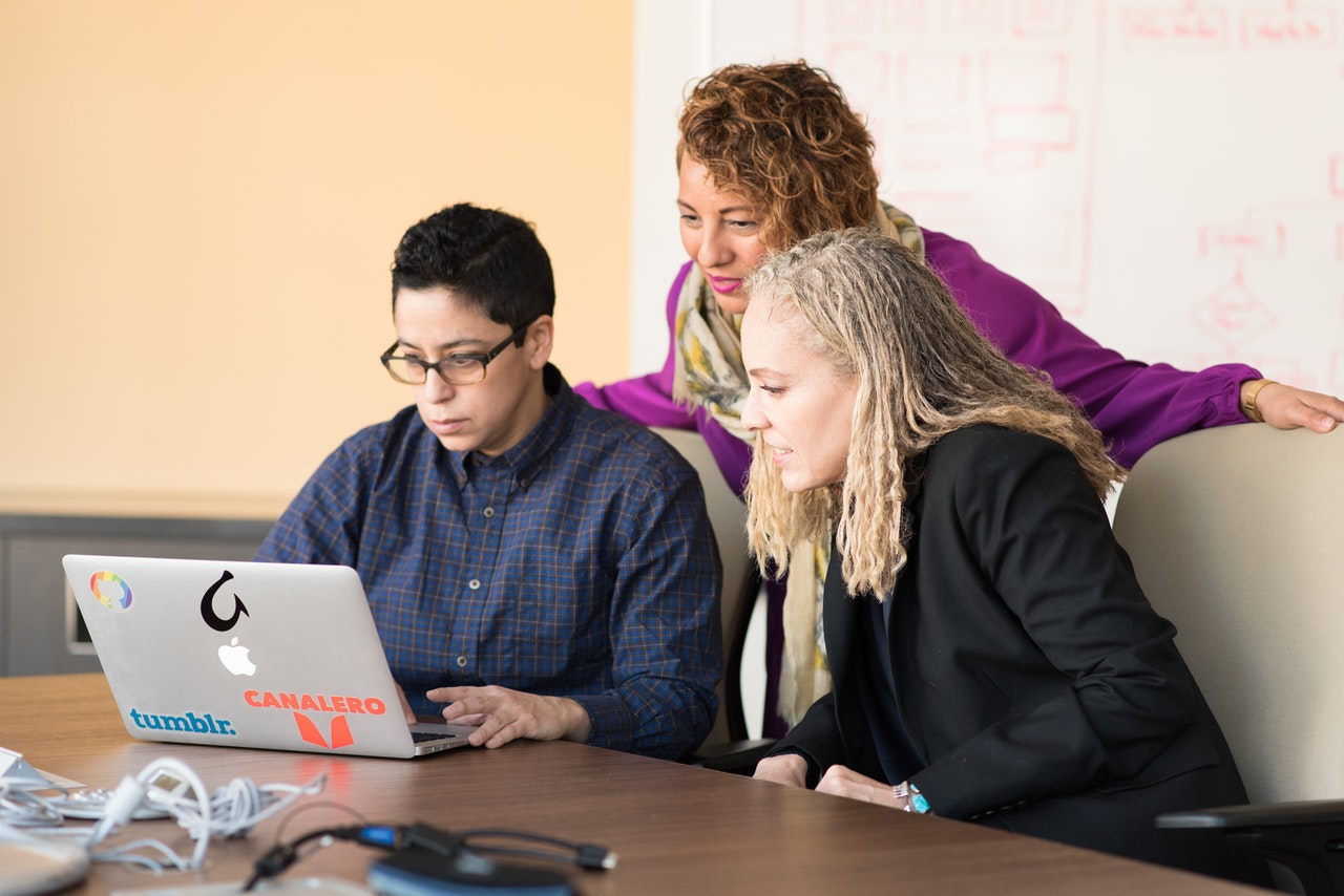 Three people centered around a laptop, gazing intently