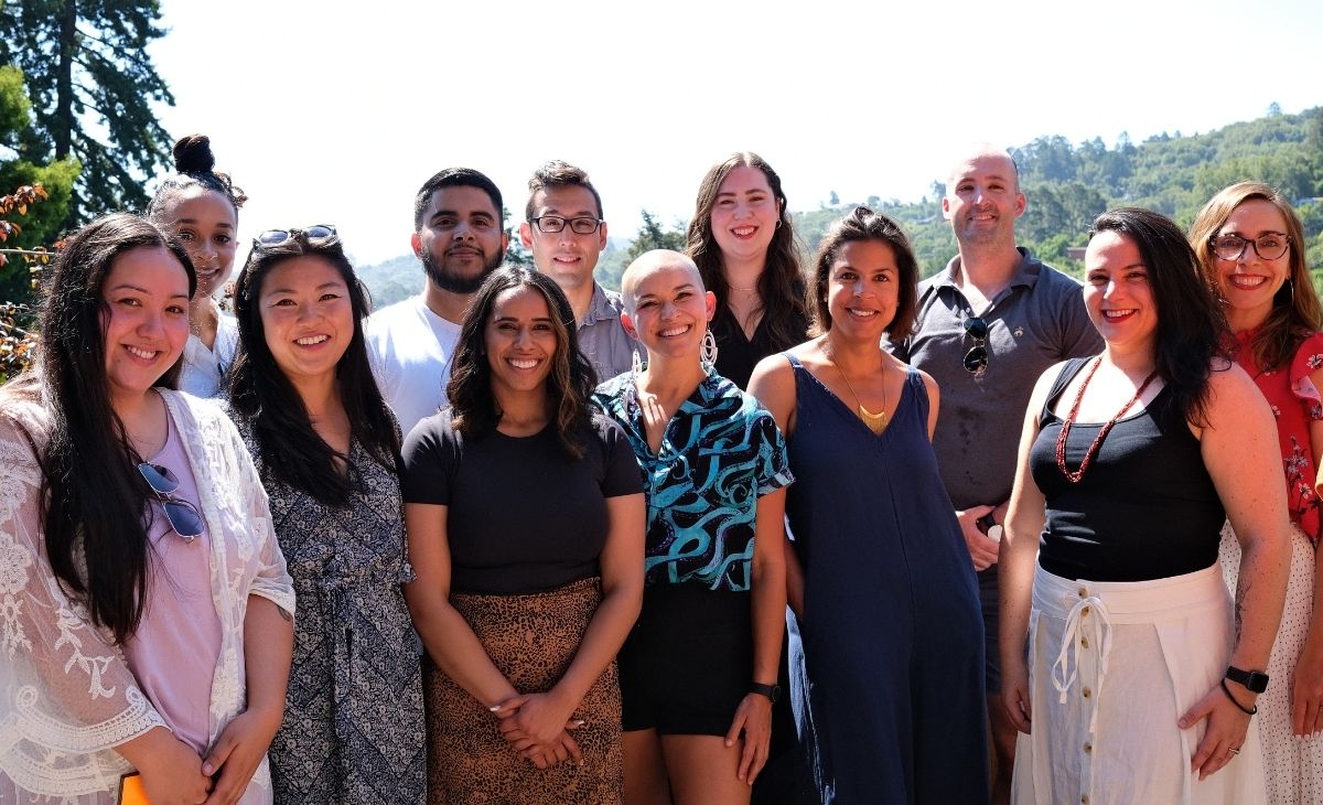 The staff of TechEquity (twelve people) standing in the sun and smiling at the camera.